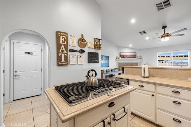 kitchen featuring a center island, light tile patterned floors, stainless steel gas cooktop, and ceiling fan