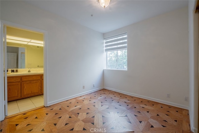 unfurnished bedroom featuring ensuite bath, light parquet floors, and sink