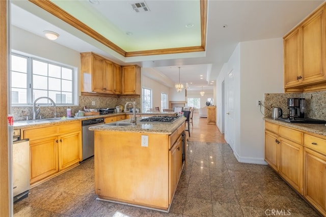 kitchen with decorative light fixtures, stainless steel appliances, a center island with sink, backsplash, and sink