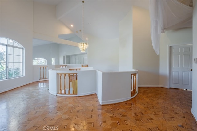 hallway with an inviting chandelier, high vaulted ceiling, and light parquet floors