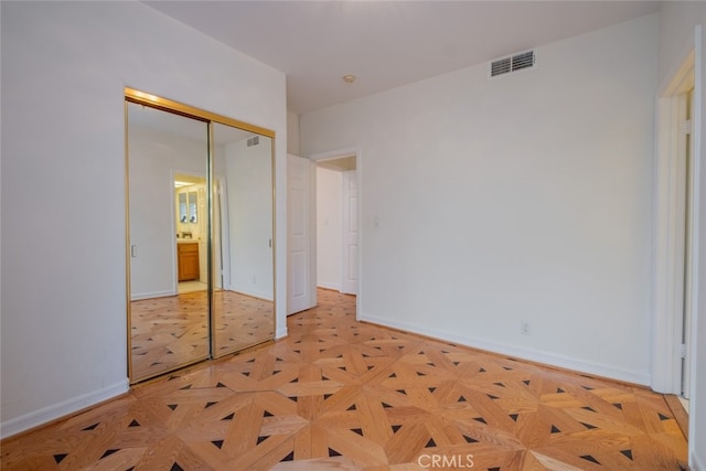 unfurnished bedroom featuring a closet and light parquet flooring