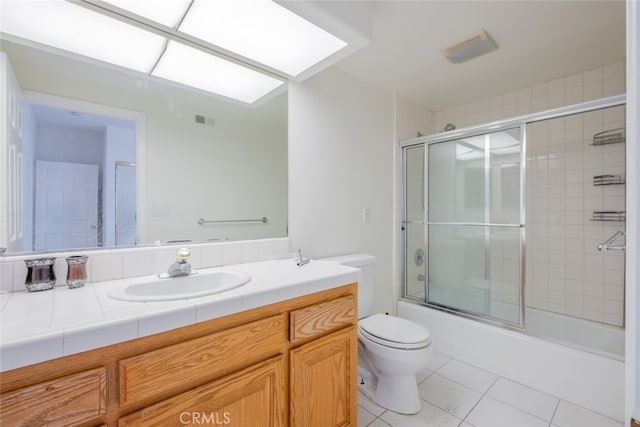 full bathroom with bath / shower combo with glass door, tile patterned floors, vanity, and toilet