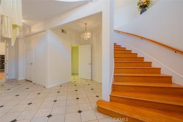 stairway featuring tile patterned flooring and a chandelier