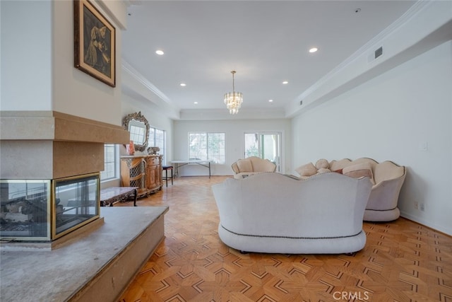 living room with a multi sided fireplace, crown molding, a chandelier, and light parquet flooring