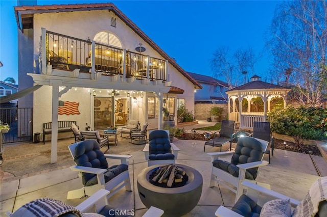 view of patio / terrace featuring a gazebo, an outdoor living space with a fire pit, a balcony, and fence