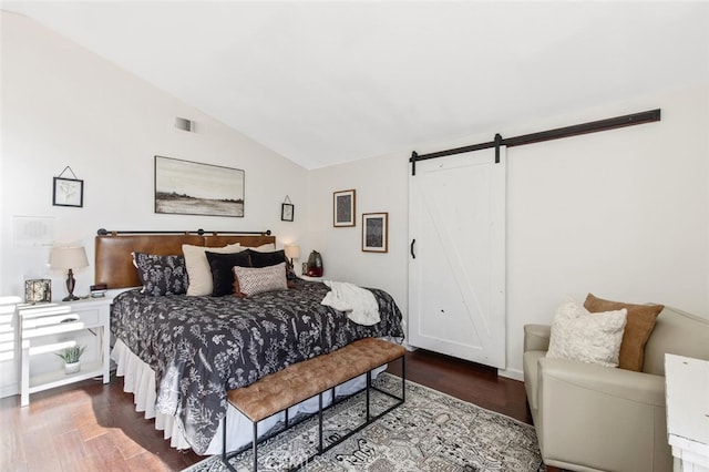 bedroom featuring lofted ceiling, a barn door, and wood finished floors