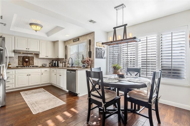 kitchen featuring visible vents, a raised ceiling, stainless steel appliances, under cabinet range hood, and white cabinetry