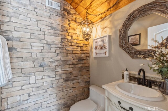 half bathroom with a chandelier, visible vents, vanity, and toilet