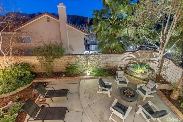 view of patio with a mountain view, a fire pit, and fence