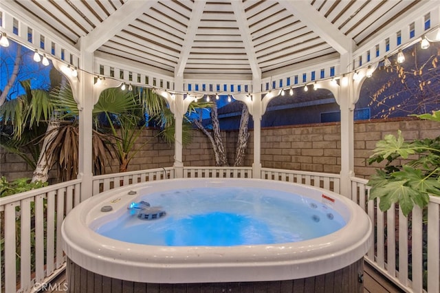 view of patio / terrace with a hot tub and fence