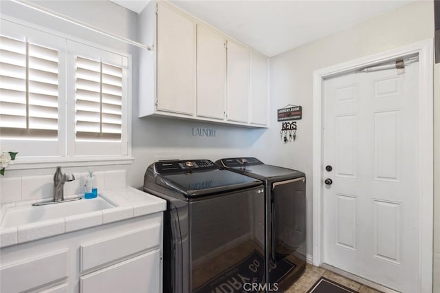 washroom with washing machine and dryer, cabinet space, and a sink