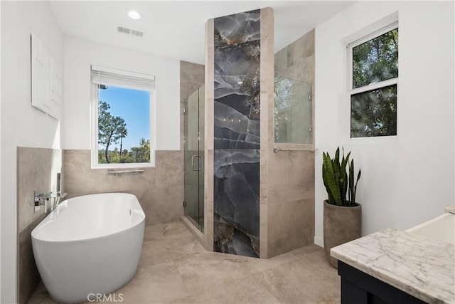 bathroom featuring tile walls, plus walk in shower, and vanity