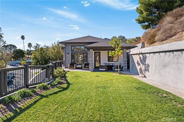 back of property with a patio area, a yard, and an outdoor living space