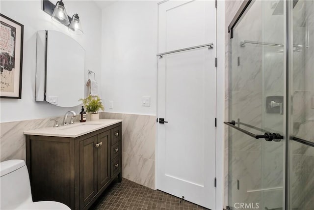 bathroom featuring tile patterned flooring, toilet, vanity, tile walls, and an enclosed shower