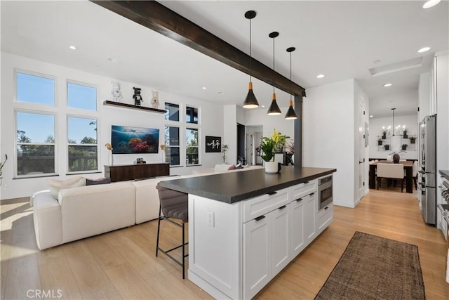 kitchen with hanging light fixtures, stainless steel appliances, a kitchen island, beam ceiling, and white cabinetry