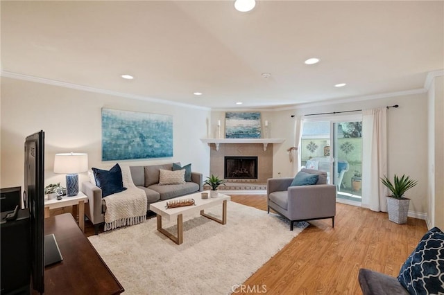 living room with a fireplace, light wood-type flooring, and ornamental molding