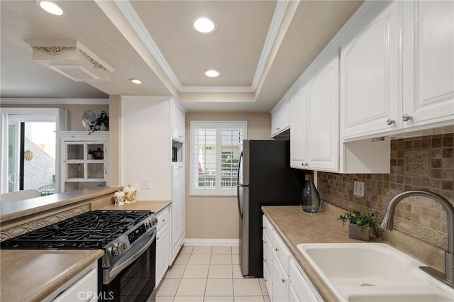 kitchen featuring stainless steel appliances, ornamental molding, a tray ceiling, sink, and white cabinetry