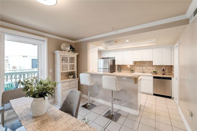 kitchen featuring stainless steel appliances, white cabinets, sink, and a raised ceiling