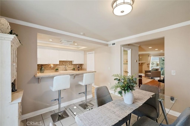 dining space with ornamental molding, sink, and light tile patterned floors