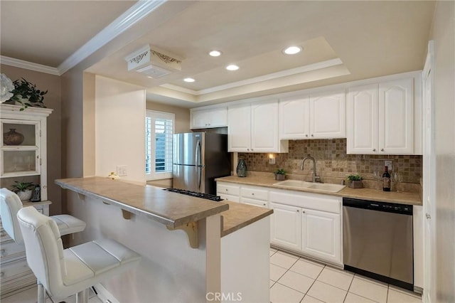 kitchen featuring sink, appliances with stainless steel finishes, a breakfast bar, and white cabinetry