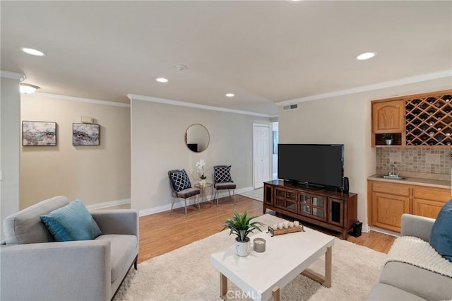 living room with light hardwood / wood-style flooring, crown molding, and indoor wet bar