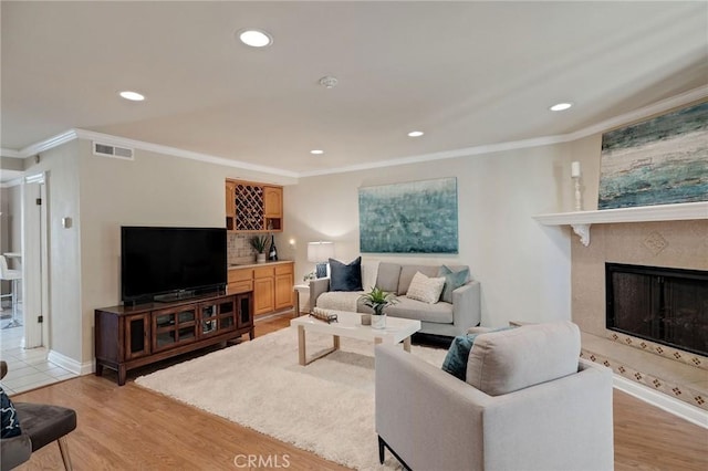 living room featuring a fireplace, light hardwood / wood-style floors, and ornamental molding