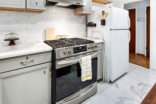 kitchen with range hood, stainless steel gas range, white fridge, and decorative backsplash