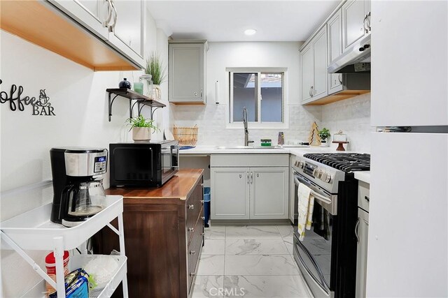 kitchen with sink, gray cabinets, stainless steel gas range, and white fridge