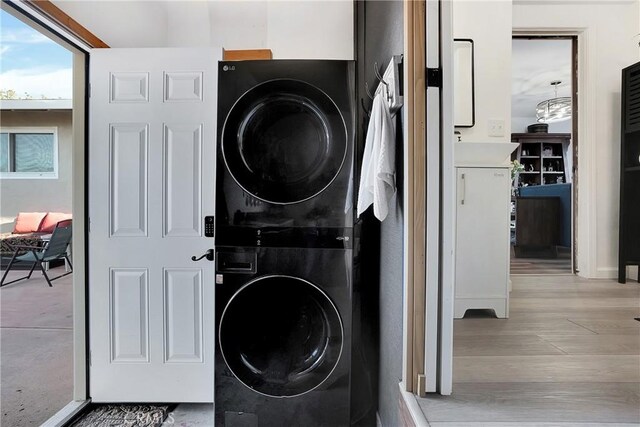 clothes washing area featuring light hardwood / wood-style flooring and stacked washer / drying machine