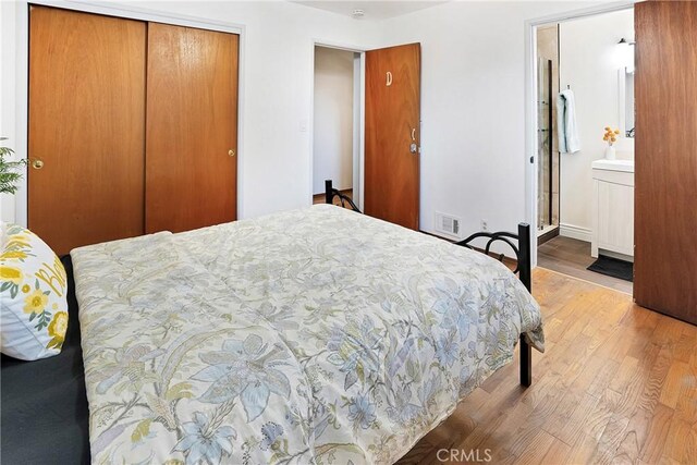 bedroom featuring light hardwood / wood-style floors, a closet, and ensuite bathroom