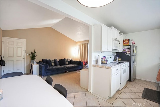 kitchen with white appliances, white cabinets, tile countertops, and light tile patterned floors