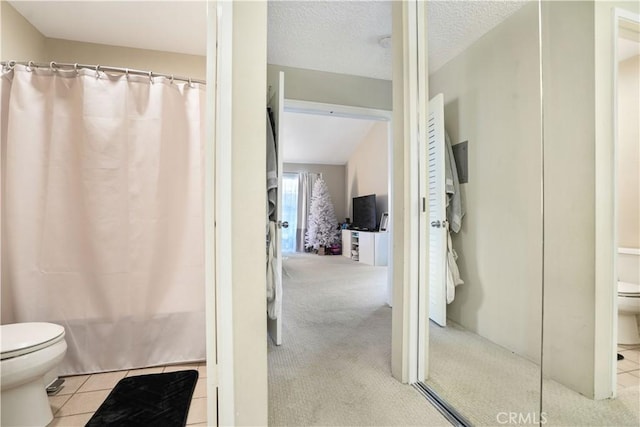 bathroom with a textured ceiling, shower / tub combo with curtain, and toilet