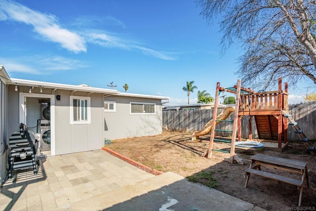 exterior space with stacked washer and dryer, a playground, and a patio area