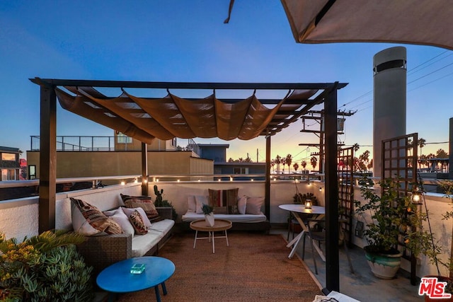 patio terrace at dusk with an outdoor hangout area, a pergola, and a balcony