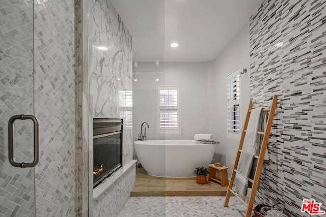 bathroom with a tiled fireplace, tile walls, tile patterned floors, and independent shower and bath