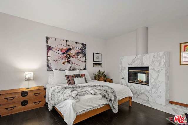 bedroom with a high end fireplace and hardwood / wood-style flooring