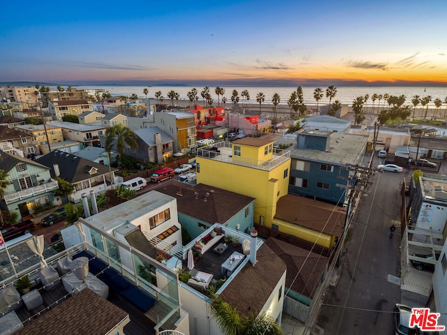 aerial view at dusk featuring a water view