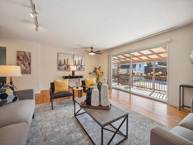 living room with wood-type flooring, track lighting, and ceiling fan