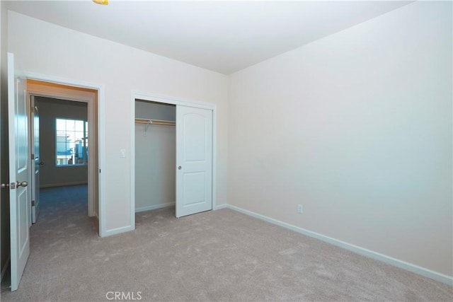 unfurnished bedroom featuring light colored carpet and a closet