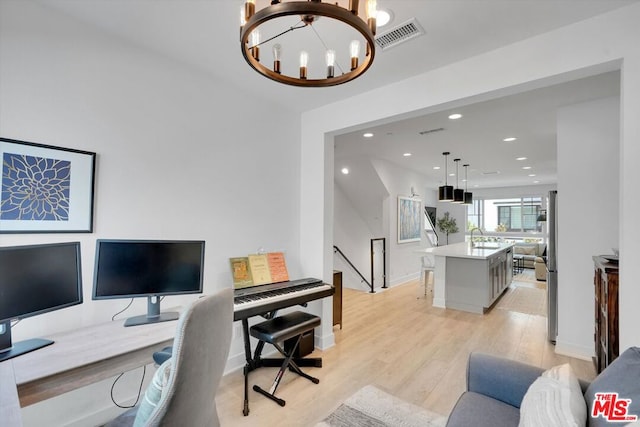 office space featuring an inviting chandelier, light hardwood / wood-style flooring, and sink