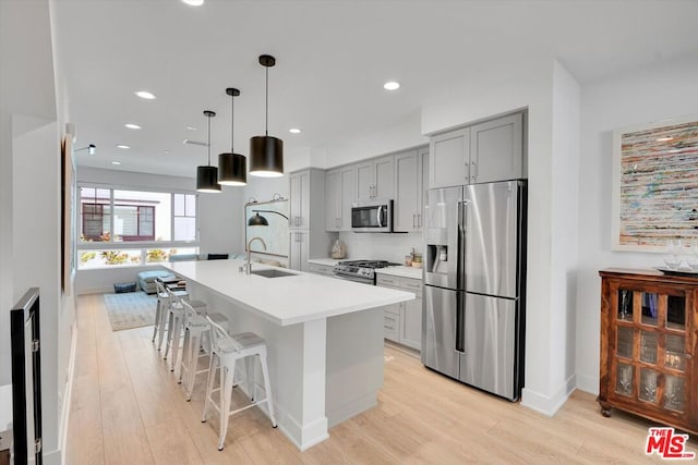 kitchen with sink, stainless steel appliances, an island with sink, and gray cabinets