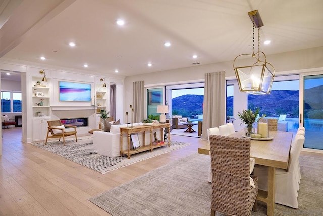 dining room featuring a notable chandelier, a wealth of natural light, built in features, and light hardwood / wood-style flooring