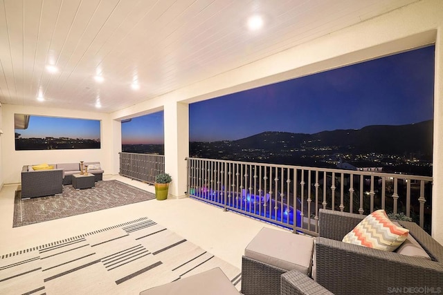 view of patio / terrace with a swimming pool, a balcony, an outdoor living space, and a mountain view