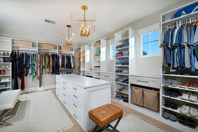 spacious closet with light wood-type flooring and a notable chandelier