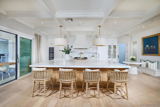 kitchen featuring decorative light fixtures, beam ceiling, premium range hood, and a spacious island