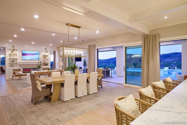 dining area with light hardwood / wood-style floors, a mountain view, and beam ceiling