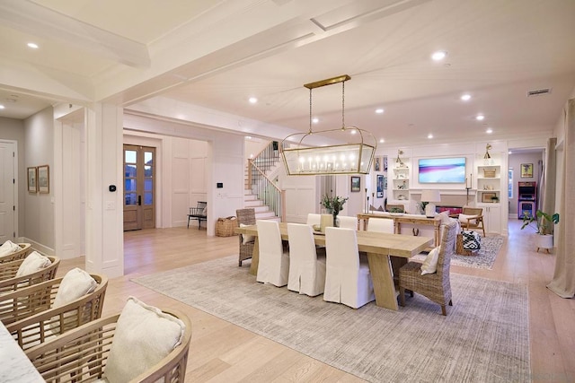 dining room featuring light hardwood / wood-style floors, beamed ceiling, and a fireplace