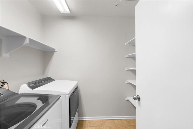 clothes washing area with light tile patterned floors and washer and dryer