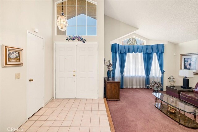 foyer featuring lofted ceiling, carpet flooring, and a textured ceiling