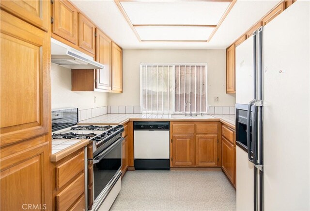 kitchen featuring white appliances, sink, and tile counters